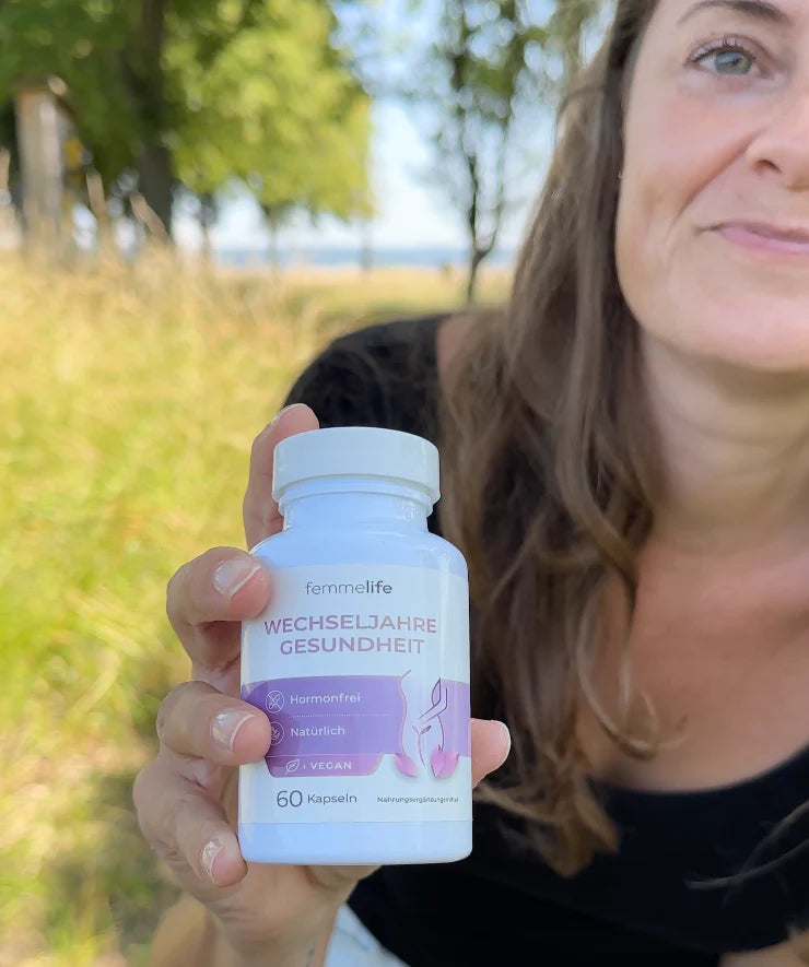 Frau hält Femmelife Wechseljahre Gesundheit Kapseln in der Natur – natürliche Hilfe bei Wechseljahresbeschwerden
